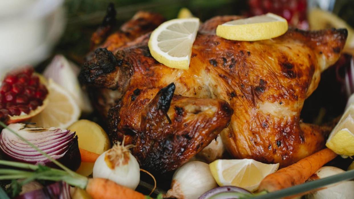  A close up image of roast turkey on a bed of vegetables. 