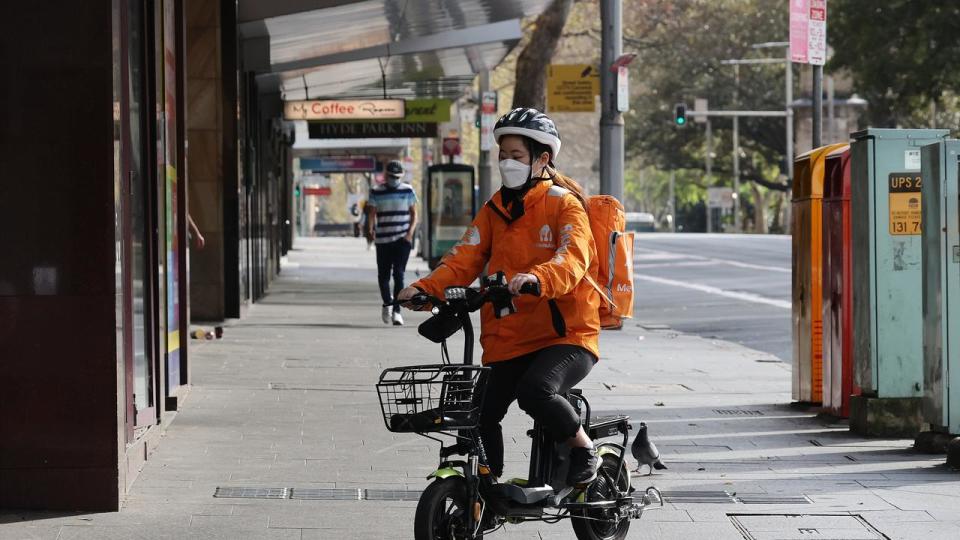 SYDNEY, AUSTRALIA - NewsWire photos AUGUST 23, 2021: A Menulog delivery person rides on the sidewalk in the Sydney CBD during COVID-19 Lockdown. Picture: NCA NewsWire / Dylan Coker