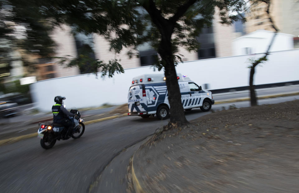 An Angels of the Road volunteer paramedic follows on a motorcycle their single ambulance transporting a patient who was injured in a road accident, in Caracas, Venezuela, Wednesday, Feb. 10, 2021. The volunteer group keeps a constant ear on walkie-talkie radio traffic and scan online chats dedicated to emergency services. (AP Photo/Ariana Cubillos)