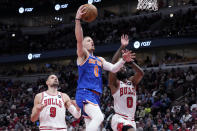 New York Knicks guard Donte DiVincenzo drives to the basket against Chicago Bulls center Nikola Vucevic, left, and guard Coby White during the first half of an NBA basketball game in Chicago, Tuesday, April 9, 2024. (AP Photo/Nam Y. Huh)