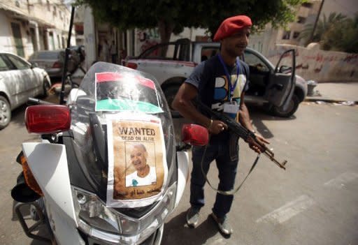 An NTC fighter stands next to a police motorcycle decorated with a doctored image of Libyan strongman Col. Moamer Kadhafi in the capital Tripoli. Fighters for Libya's new rulers on Saturday began an assault to overrun a bastion of Moamer Kadhafi, as secret files shed light on his fallen regime's links to US and British spy agencies