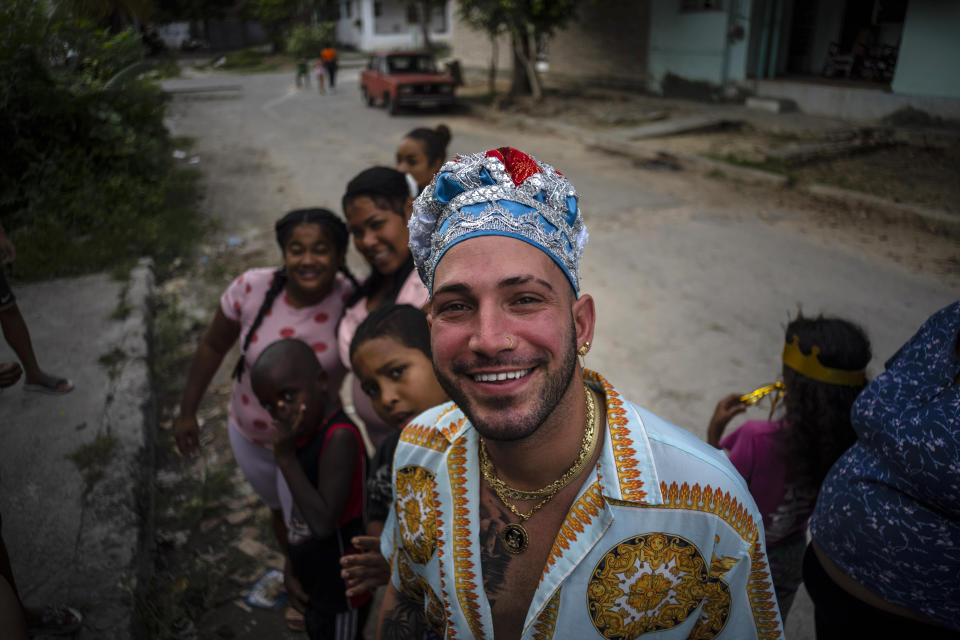 Mandy Arrazcaeta, dressed for a Santería ceremony, smiles for the camera outside his home in Havana, Cuba, Sunday, Nov. 13, 2022. “Every day the religion grows a little more,” Mandy Arrazcaeta, 30, said. “Right now, Santería in the country is a sort of bastion.” (AP Photo/Ramon Espinosa)