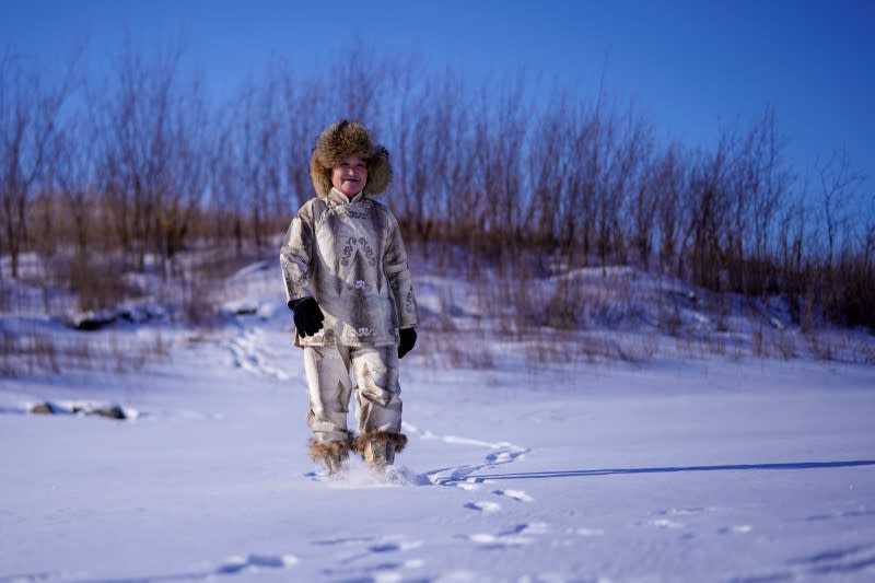 You Wenfeng, 68, an ethnic Hezhen woman, poses with her fishskin clothes at a frozen river in Tongjiang