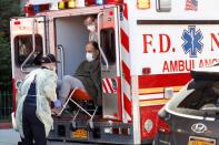 FDNY Emergency Medical Technicians (EMT) lift a patient that was identified to have coronavirus disease (COVID-19) in New York