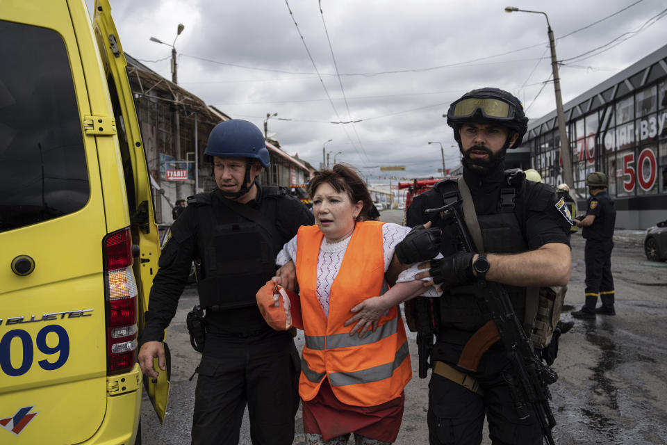 Police officers help a woman after Russian shelling at Barabashovo market in Kharkiv, Ukraine, Thursday, July 21, 2022. (AP Photo/Evgeniy Maloletka)