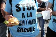 An activist wearing a sweeter reading "Stop discrimination" holds a home-made hamburger during a demonstration outside of a McDonald's restaurant, Thursday, Aug. 22, 2019 in Hendaye, southwestern France. The G-7 summit has for the first time co-opted the message of its protesters: Capitalism has led to damaging inequality, hurting the environment also harms the global economy, and a handful of rich countries can't be the only ones making decisions for the world. (AP Photo/Bob Edme)