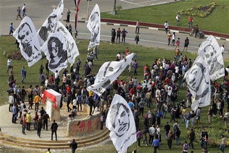 People wave banners depicting people who died in previous Egyptian revolutions around a monument, erected in honour of the victims, draped with an Egyptian flag after security forces fired teargas at protesters in Tahrir square in downtown Cairo November 19, 2013. REUTERS/Mohamed Abd El Ghany