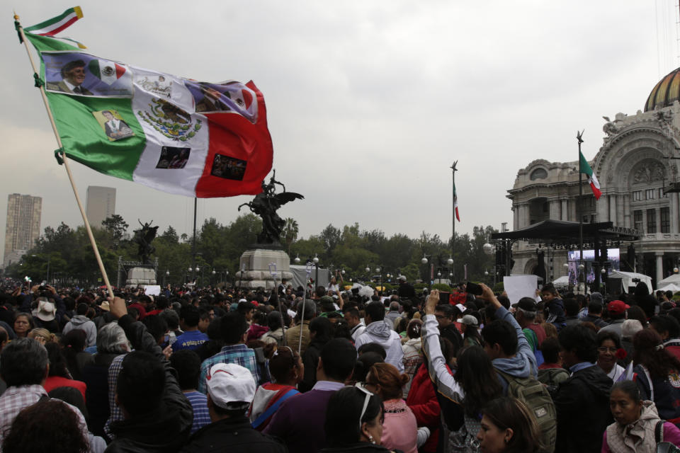 A man waves a Mexican flag with photographs of Mexican singer Juan Gabriel during the Memorial at Palacio de Bellas Artes.