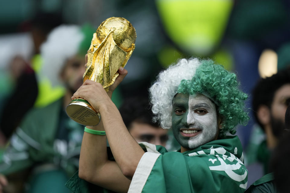 A Saudi Arabia fan holds up a copy of the World Cup trophy prior of the World Cup group C soccer match between Poland and Saudi Arabia, at the Education City Stadium in Al Rayyan , Qatar, Saturday, Nov. 26, 2022. (AP Photo/Francisco Seco)