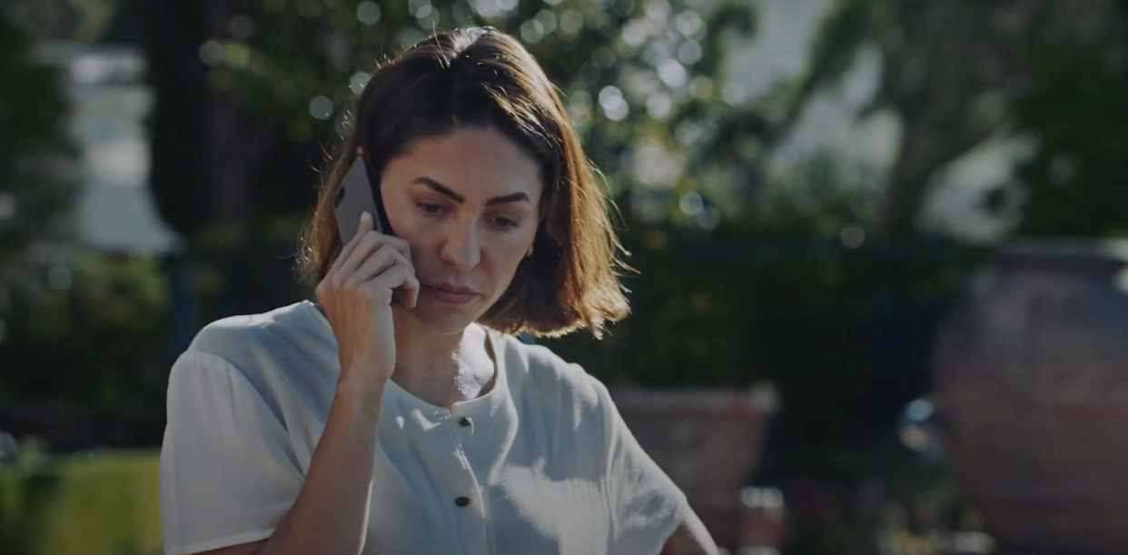 natalia cordova buckley as sofia in the portrait, a woman stands outside talking on a mobile