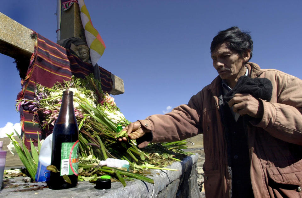 Porfirio Pakiricona places a gift of coca leaves on an altar in La Cumbre, a place in the Andes Mountain where Bolivians leave gifts for La Pachamama (Mother Earth), Saturday, Aug. 3, 2002. During August, people leave offerings of flowers, alcohol, and coca leaves to deities, as a way to give thanks and asking for favors. (AP Photo/Dolores Ochoa)