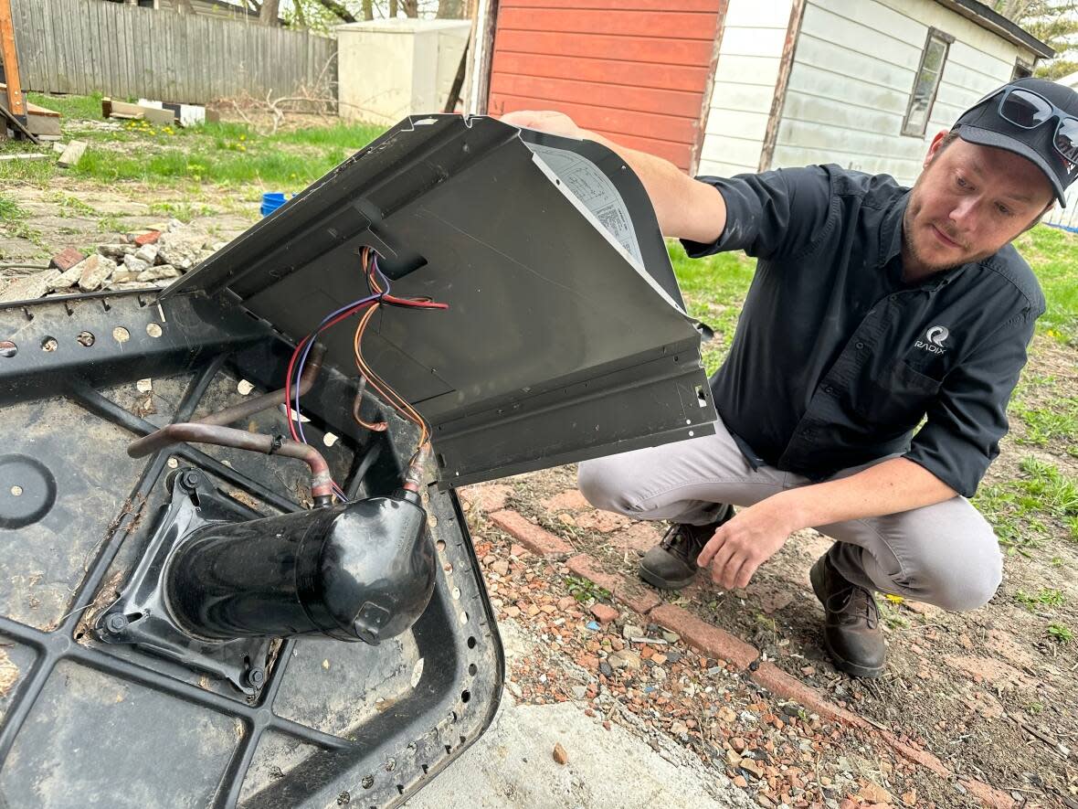 Ryan Rawlings inspects what's left of the air conditioner behind his house on Curry Avenue in Windsor. (Dale Molnar/CBC - image credit)