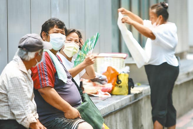 全台氣溫飆升，27日各地出現30度以上高溫，昨用電飆破歷史紀錄，創下新高，中午有民眾坐在路旁搧風納涼。（鄧博仁攝）