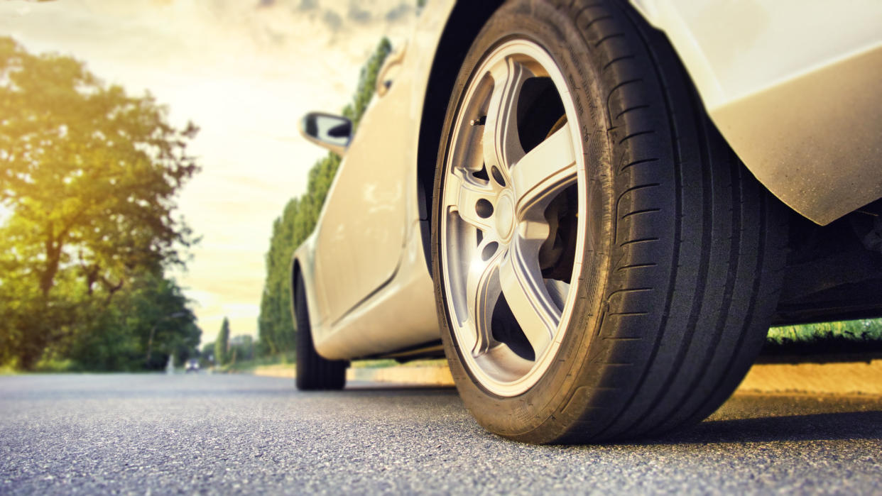 Car tire close up on asphalt road at sunset