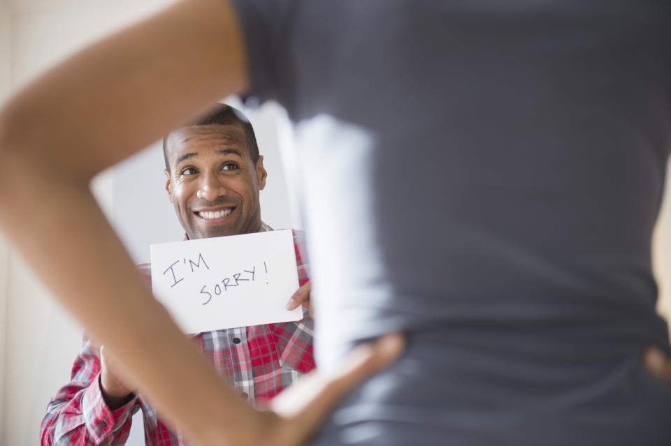 A man holding a paper that says, "I'm sorry!"