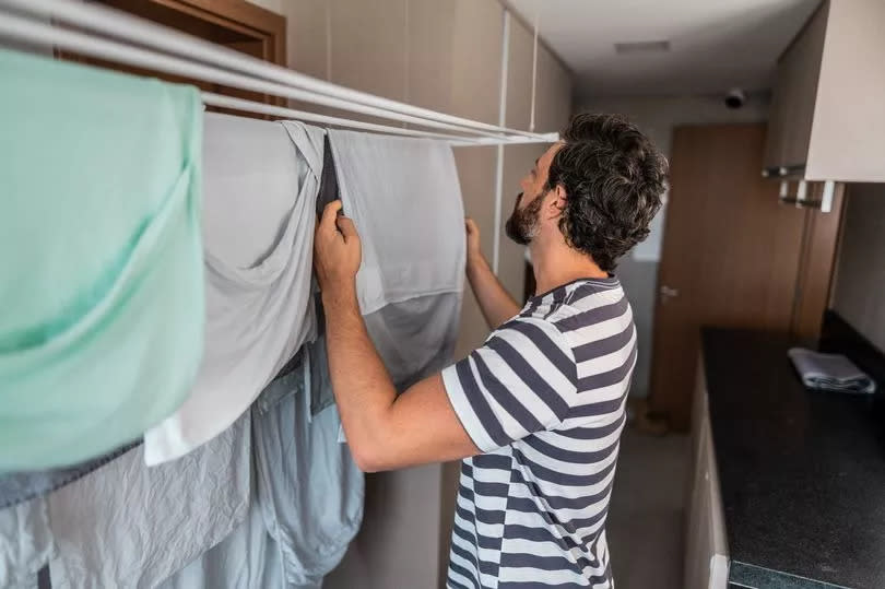 Mid adult man hanging laundry on clothesline at home.