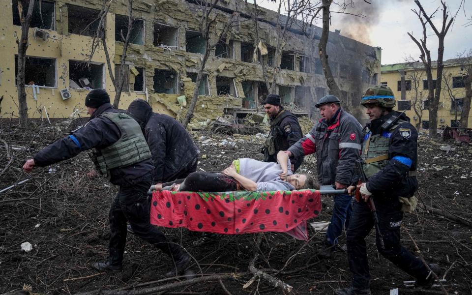 Ukrainian emergency employees and volunteers carry an injured pregnant woman from a maternity hospital that was damaged by shelling in Mariupol, Ukraine