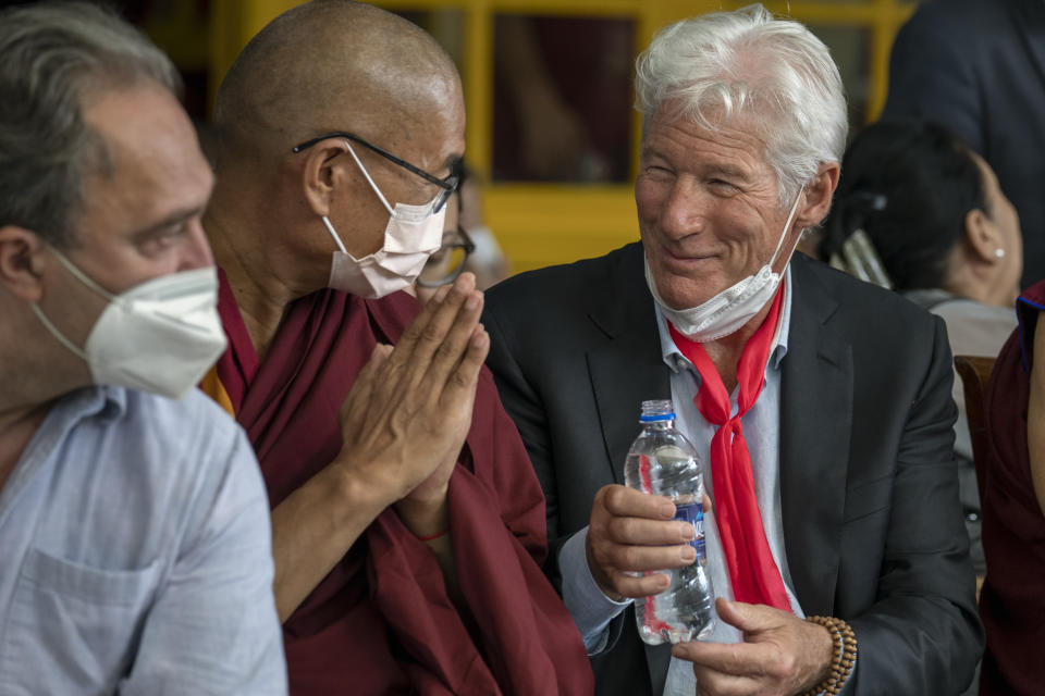 Hollywood actor Richard Gere offers water to a Buddhist monk sitting next to him as he attends an event to mark the 87th birthday of Tibetan spiritual leader the Dalai Lama in Dharmsala, India, Wednesday, July 6, 2022. (AP Photo/Ashwini Bhatia)