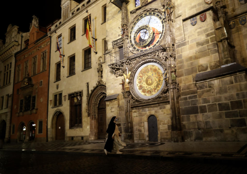 A nun walks past the Astronomical Clock on a near empty Old Town Square in Prague, Czech Republic, Friday, Oct. 23, 2020. In much of Europe, city squares and streets, be they wide, elegant boulevards like in Paris or cobblestoned alleys in Rome, serve as animated evening extensions of drawing rooms and living rooms. As Coronavirus restrictions once again put limitations on how we live and socialize, AP photographers across Europe delivered a snapshot of how Friday evening, the gateway to the weekend, looks and feels. (AP Photo/Petr David Josek)
