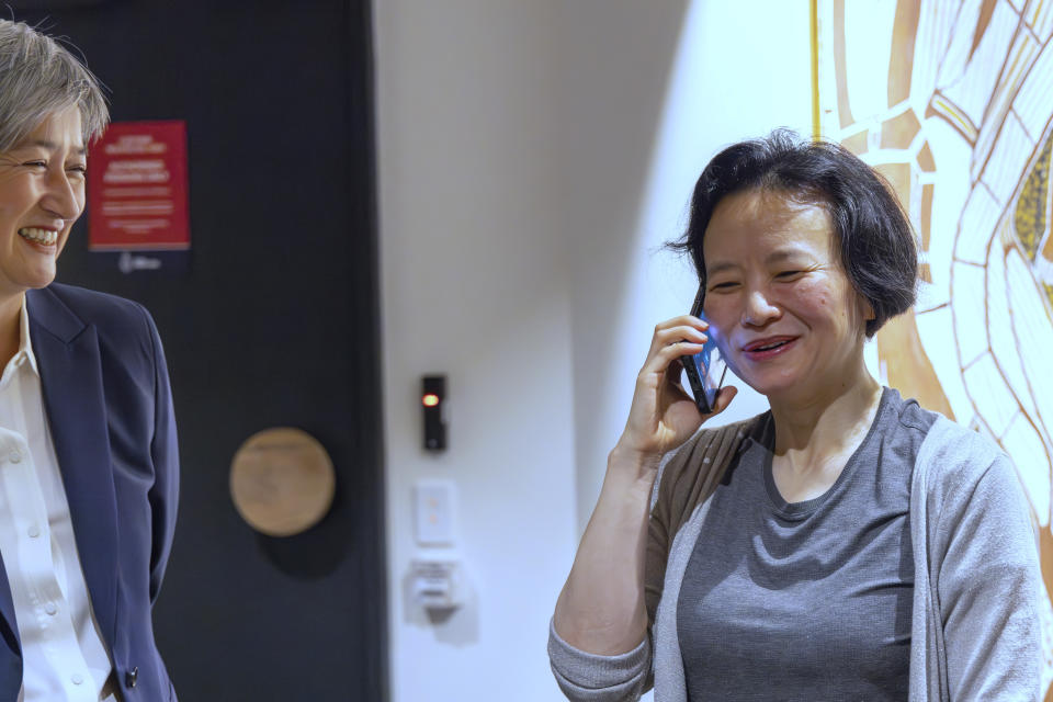 In this photo provided by the Department of Foreign Affairs and Trade, Chinese Australian journalist Cheng Lei, right, talks on the phone as Australia's Minister for Foreign Affairs, Penny Wong, watches at Tullamarine Airport in Melbourne, on Wednesday Oct. 11, 2023. Cheng, who was convicted on murky espionage charges and detained in China for three years has returned to Australia. (Sarah Hodges/DFAT via AP)