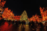 FILE - Visitors stand in front of the illuminated Christmas tree at the Winter Wonder and Christmas Market on the Grand Place in Brussels, Belgium, Nov. 25, 2022. In cities across Europe, officials are wrestling with a choice this Christmas. Dim lighting plans to send a message of energy conservation and solidarity with citizens squeezed by both higher energy costs and inflation or let the lights blaze in a message of defiance after two years of pandemic-suppressed Christmas seasons, creating a mood that retailers hope loosen holiday purses. (AP Photo/Olivier Matthys, File)