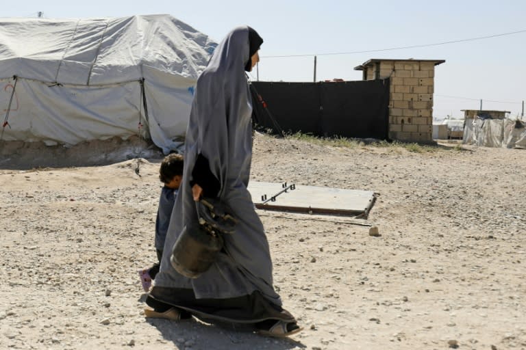 A woman walks with a child at a camp for people linked to the Islamic State group in the village of Malikiya in northern Syria near the border with Turkey on September 29, 2018