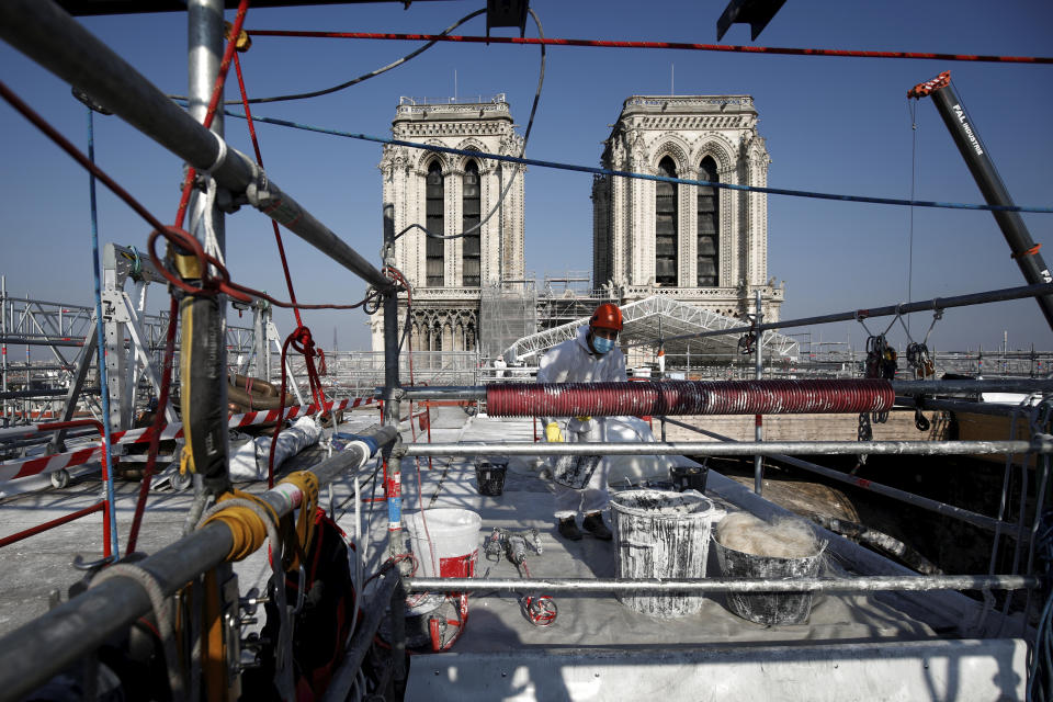 A worker at the reconstruction site of the Notre-Dame cathedral, Thursday, April 15, 2021 in Paris. Two years after a fire tore through Paris' most famous cathedral and shocked the world, French President Emmanuel Macron is visiting the building site that Notre Dame has become Thursday to show that French heritage has not been forgotten despite the coronavirus. (Benoit Tessier/Pool via AP)