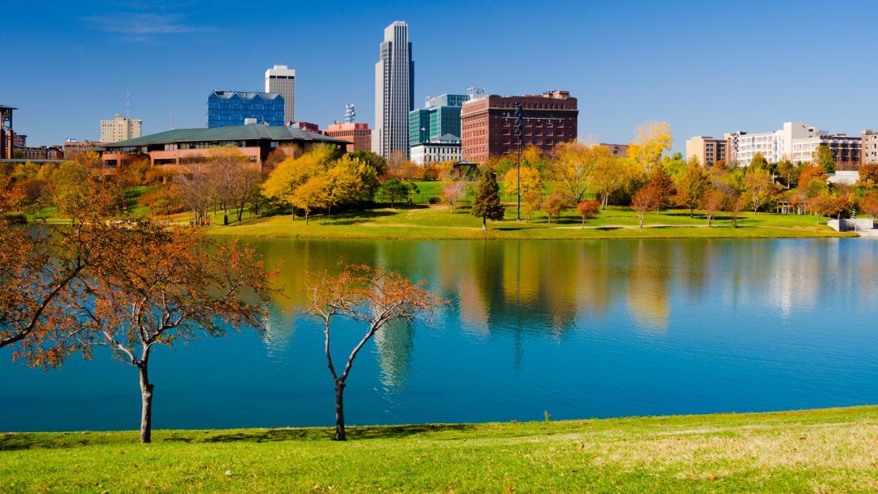 Downtown Omaha skyline with the Heartland of America Park (with a lake and fall colored trees) in the foreground.