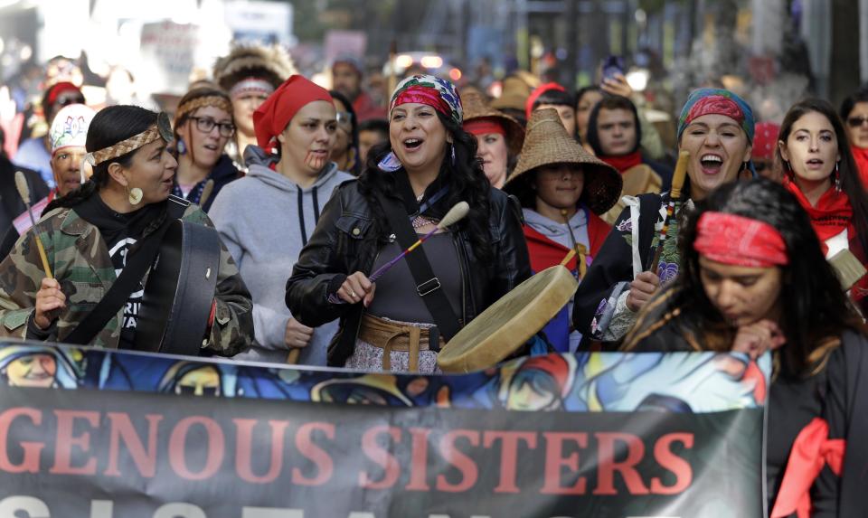 FILE - Women drummers sing as they lead a march during an Indigenous Peoples Day event, Oct. 9, 2017, in Seattle. Members of the Native American Journalists Association are voting on whether to change the name to the Indigenous Journalists Association. (AP Photo/Elaine Thompson, file)