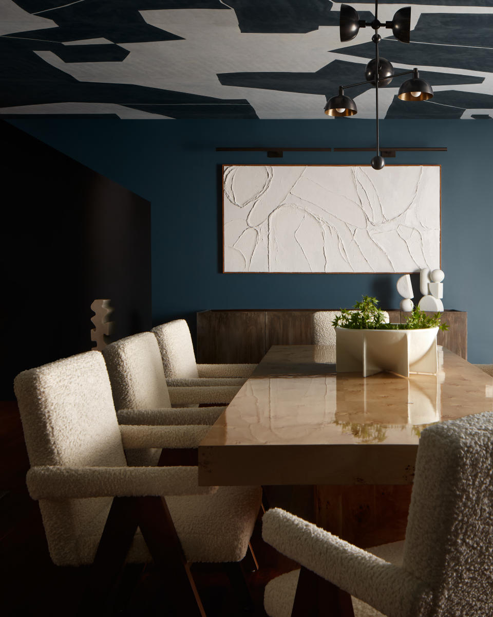 blue dining room with white chairs, white artwork and monochrome wallpaper on the ceiling