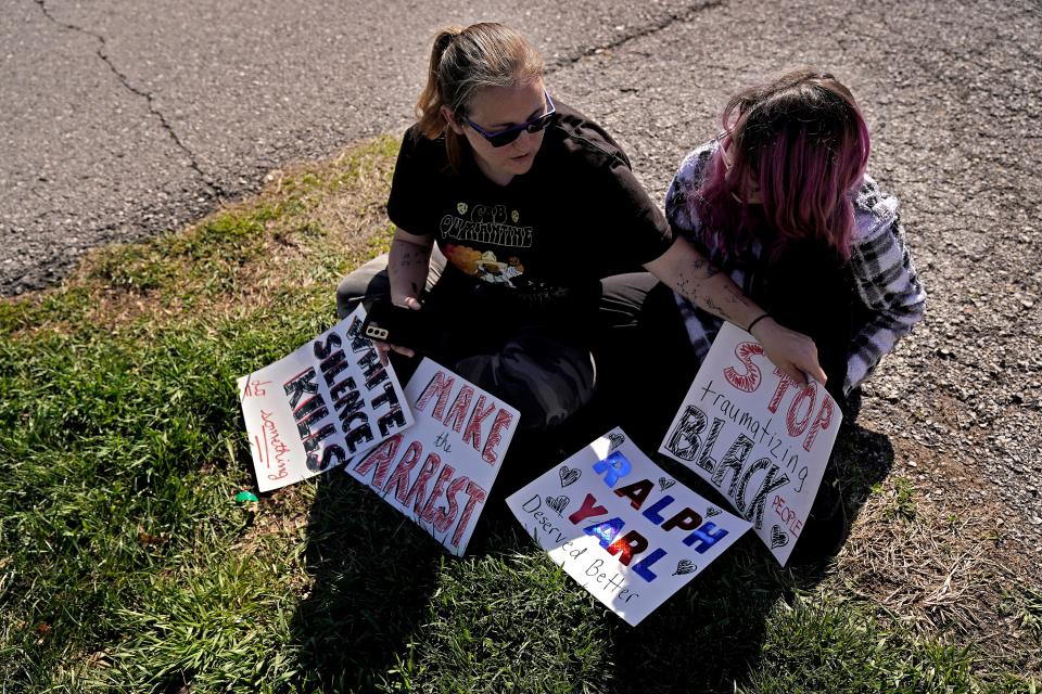 protestors sit on the ground with signs about shooting of Ralph Yarl