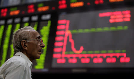 FILE PHOTO: A man monitors an electronic board displaying stock prices at the Karachi Stock Exchange August 5, 2011. Pakistani stocks provisionally ended 3.78 percent lower on Friday as foreign investors offloaded their holdings amid a global sell-off, while local investors remained cautious, dealers said. REUTERS/Akhtar Soomro/File Photo