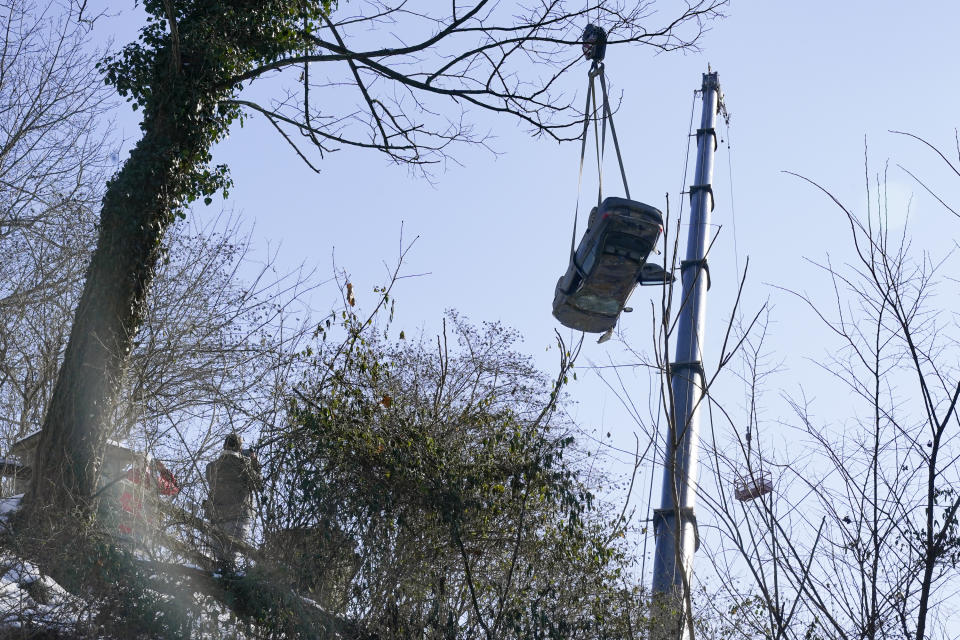 A car is lifted by crane during the recovery process on Monday Jan. 31, 2022 of a bus and other vehicles that were on a bridge when it collapsed Friday, in Pittsburgh's East End. (AP Photo/Gene J. Puskar)