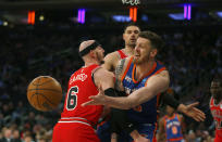 New York Knicks center Josh Hartenstein, right, passes the ball around Chicago Bulls guard Alex Caruso, left, during the first half of an NBA basketball game Sunday, April 14, 2024, in New York. (AP Photo/John Munson)