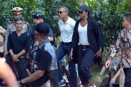 Former United States President Barack Obama and his wife Michelle walk during a visit to Tirta Empul Temple while on holiday with his family in Gianyar, Bali, Indonesia June 27, 2017 in this photo taken by Antara Foto. Antara Foto/Wira Suryantala/ via REUTERS