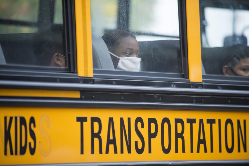FILE - In this Oct. 12, 2020, file photo, students arrive by bus at Foundation Preparatory School for their return to school during the coronavirus in New Orleans. With COVID-19 cases soaring nationwide, school districts across the U.S. are yet again confronting the realities of a polarized country and the lingering pandemic as they navigate mask requirements, vaccine rules and social distancing requirements for the fast-approaching new school year. (Chris Granger/The Times-Picayune/The New Orleans Advocate via AP, File)