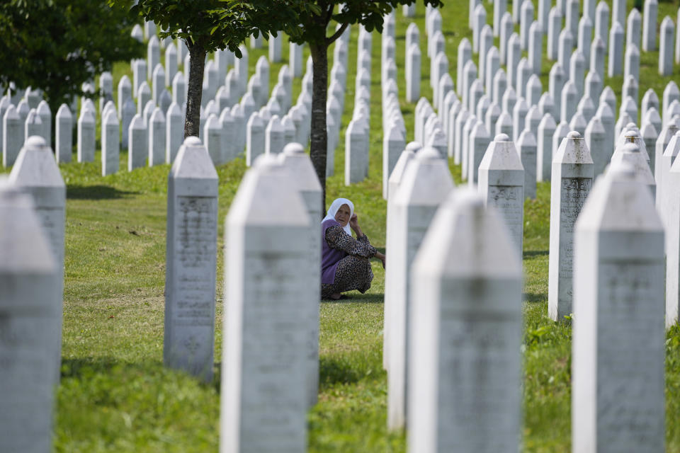 A woman crouches among the graves of victims of the Srebrenica massacre, at the memorial cemetery in Potocari, near Srebrenica, eastern Bosnia, Tuesday, June 8, 2021. Tuesday the United Nations court in The Hague, Netherlands, delivers its verdict in the appeal by former Bosnian Serb military chief Ratko Mladic against his convictions for genocide and other crimes and his life sentence for masterminding atrocities throughout the Bosnian war. (AP Photo/Darko Bandic)