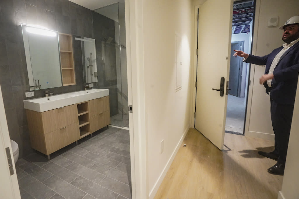 Malek Hajar, senior project manager at the Vanbarton Group, shows a bathroom inside a model apartment while touring a high rise undergoing conversion from commercial to residential apartments, Tuesday, April 11, 2023, in New York.