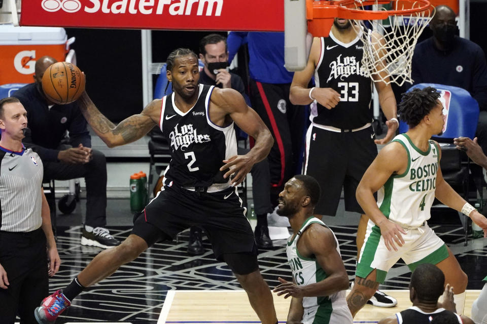 Los Angeles Clippers forward Kawhi Leonard (2) passes the ball next to Boston Celtics guard Kemba Walker, center, during the second half of an NBA basketball game Friday, Feb. 5, 2021, in Los Angeles. (AP Photo/Marcio Jose Sanchez)