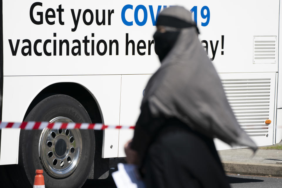 A woman queues to receive a COVID-19 vaccination at the ESSA Academy in Bolton, England, Tuesday May 18, 2021. For the first time in months, people across England are meeting indoors at pubs, restaurants, cinemas, gyms and elsewhere as coronavirus rules were relaxed across the country on Monday. But Prime Minister Boris Johnson warned Britons to be cautious and some of the scientists advising him say restrictions might need to be reimposed quickly because of a worrying variant first detected in India. (AP Photo/Jon Super)