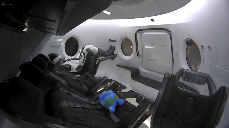 This Saturday, March 2, 2019 image from video made available by SpaceX shows a life-size test mannequin and a stuffed toy in the Dragon capsule as the it launches into orbit en route to the International Space Station, arriving 27 hours after liftoff. (SpaceX via AP)