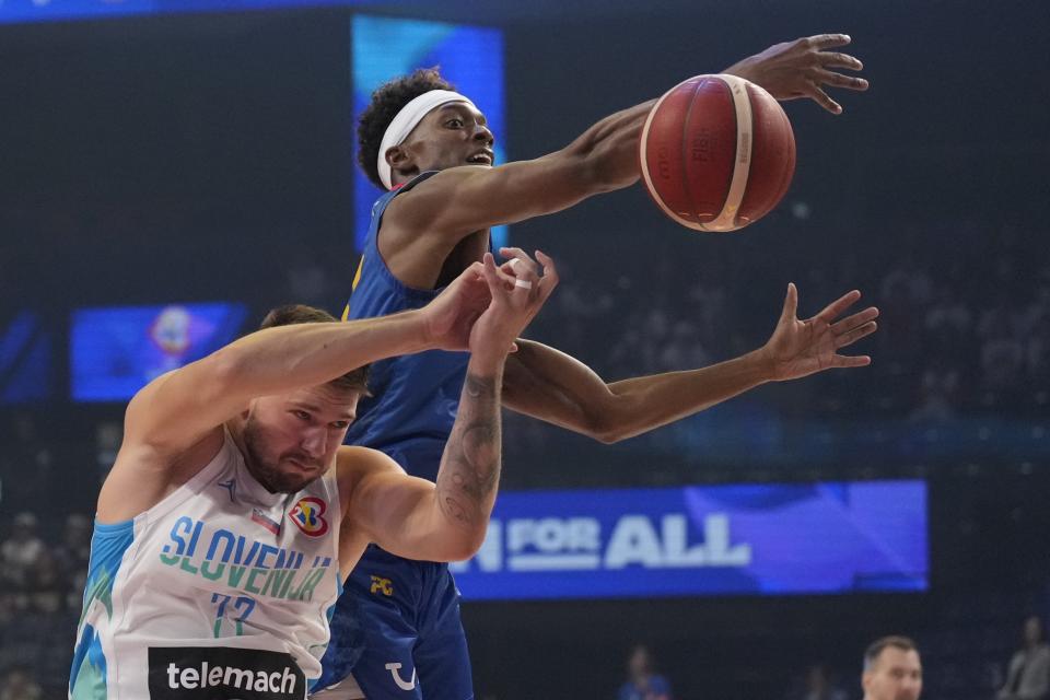 Slovenia guard Luka Doncic (77) and Cape Verde forward Will Tavares (13) fight for a loose ball in the first half of their Basketball World Cup group F match in Okinawa, southern Japan, Wednesday, Aug. 30, 2023. (AP Photo/Hiro Komae)