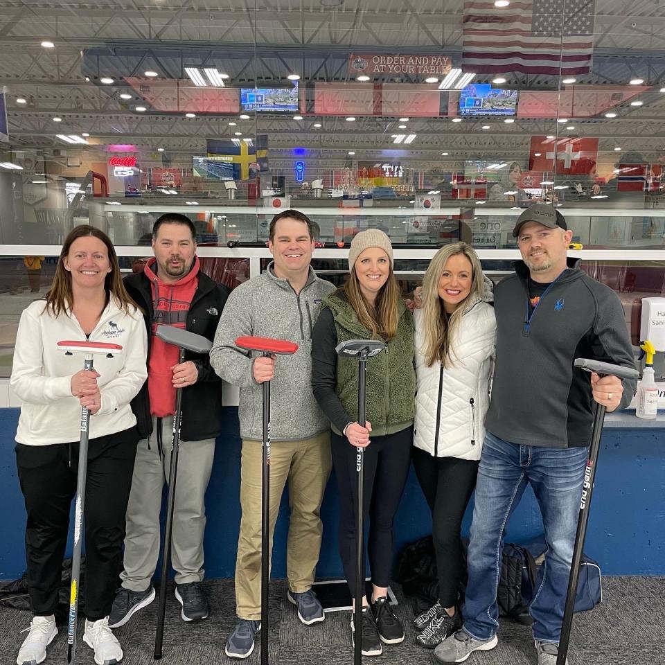 Sartell residents Penny Leen, Steve Leen, Nate Dahl, Jessica Dahl (NSCC Vice President), Theresa Haugen, and Kasey Haugen hold their Curling "brooms" at a Learn to Curl event in Blaine.