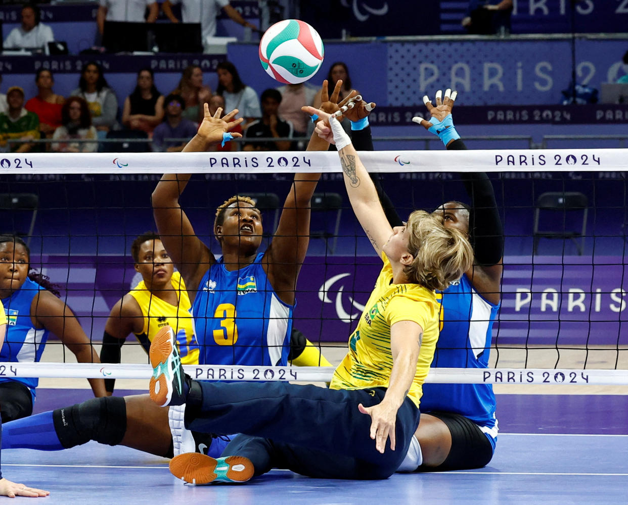 Women competing in sitting volleyball.