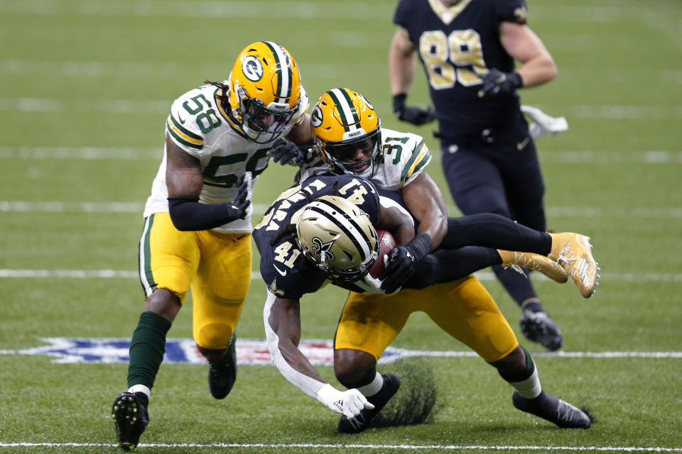 New Orleans Saints running back Alvin Kamara (41) is tackled by Green Bay Packers strong safety Adrian Amos (31) and inside linebacker Christian Kirksey (58) on a 49 yard run in the first half of an NFL football game in New Orleans, Sunday, Sept. 27, 2020. (AP Photo/Brett Duke)