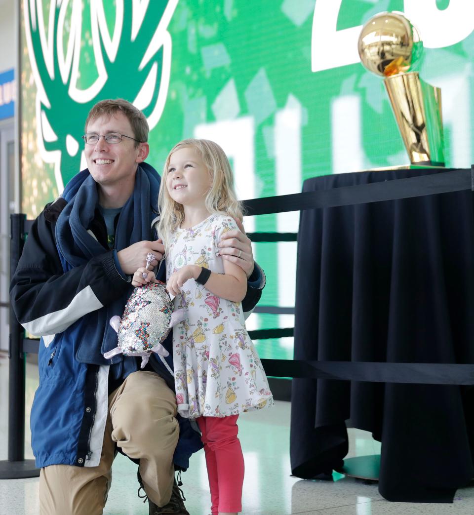 Grace Shaffer, 5, and her dad Josh Shaffer of New Berlin pose for a photo in front of the Larry O'Brien NBA championship trophy after Grace received the COVID-19 vaccine Saturday at Fiserv Forum.