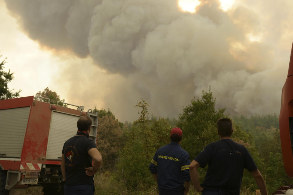 Smoke rises from a forest as firefighters look on in Giannouli village, in the northeastern Evros region, Greece, Thursday, Aug. 31, 2023. Greek authorities have further reinforced firefighting forces in the country's northeast, where a massive blaze in its thirteenth day has flared up once more, triggering authorities to issue alerts to residents in the area to be on standby for possible evacuation. (e-evros.gr via AP)