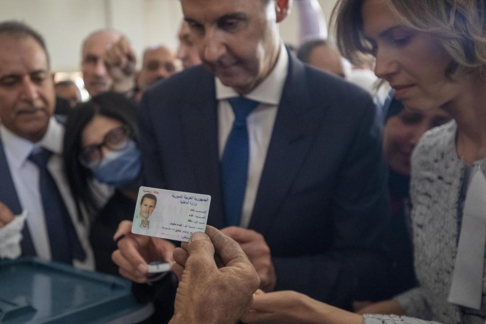 A Syrian election official checks the ID of Syrian President Bashar Assad and his wife Asma before they cast their votes at a polling station during the Presidential elections in the town of Douma, in the eastern Ghouta region, near the Syrian capital Damascus, Syria, Wednesday, May 26, 2021. Syrians headed to polling stations early Wednesday to vote in the second presidential elections since the deadly conflict began in the Arab country. (AP Photo/Hassan Ammar)