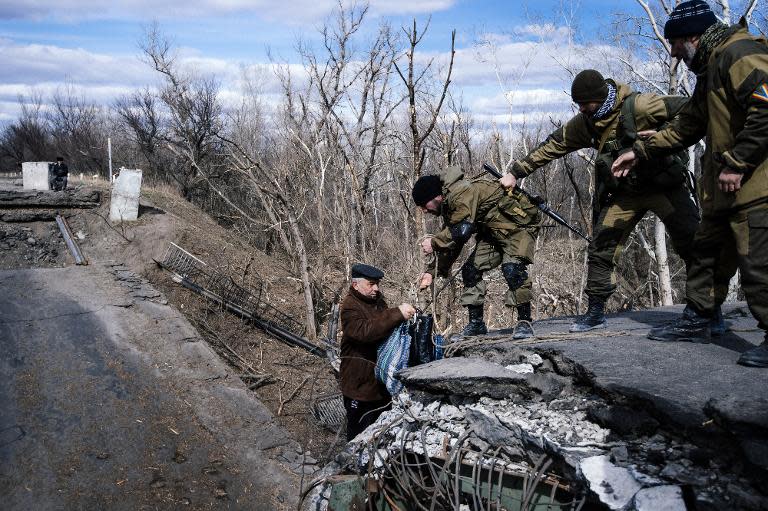 Pro-Russian rebels help an elderly man to climb on a damaged bridge across the Siversky Donets river near the village of Stanytsia Luhanska, on March 23, 2015