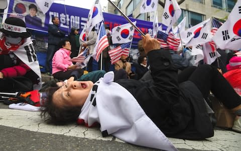 Outside the court, a supporter of the former president reacted to the leader's sentence - Credit: Jung Yeon-je/AFP